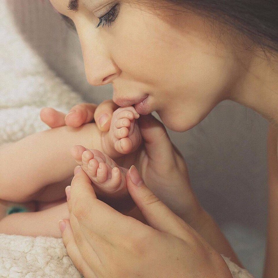 Мама целует ножки младенца